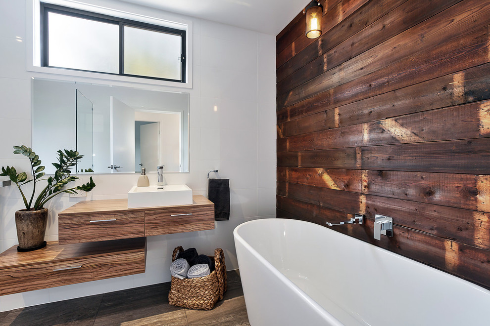 Стильный дизайн: главная ванная комната в современном стиле с плоскими фасадами, фасадами цвета дерева среднего тона, отдельно стоящей ванной, белыми стенами, настольной раковиной и коричневым полом - последний тренд