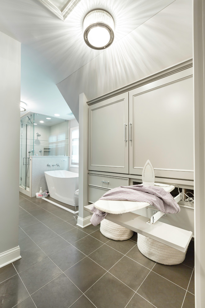 Example of a mid-sized transitional master brown tile and stone tile limestone floor freestanding bathtub design in Chicago with an undermount sink, flat-panel cabinets, gray cabinets, quartzite countertops, a two-piece toilet and gray walls