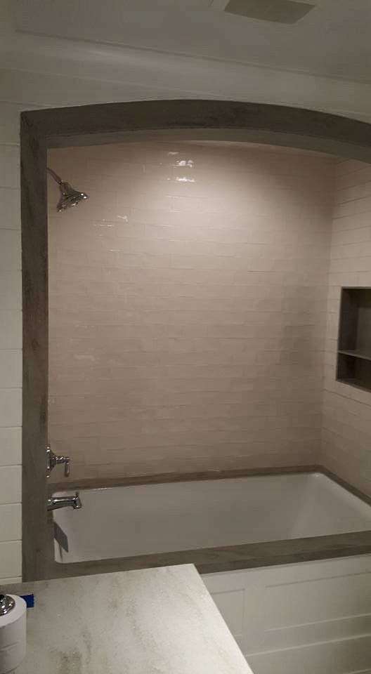 Bild på ett mellanstort vintage badrum med dusch, med luckor med infälld panel, vita skåp, ett badkar i en alkov, en dusch/badkar-kombination, vit kakel, tunnelbanekakel, mosaikgolv, ett undermonterad handfat och brunt golv