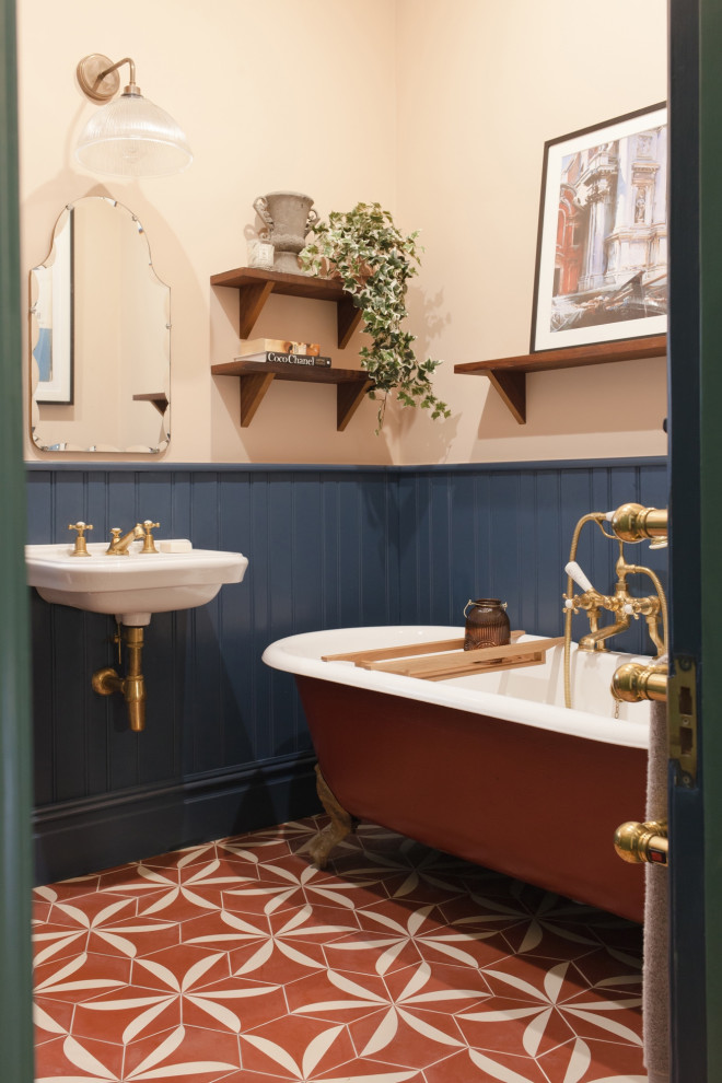 Immagine di una stanza da bagno chic con vasca con piedi a zampa di leone, pareti multicolore, pavimento in cementine, lavabo sospeso e pavimento rosso