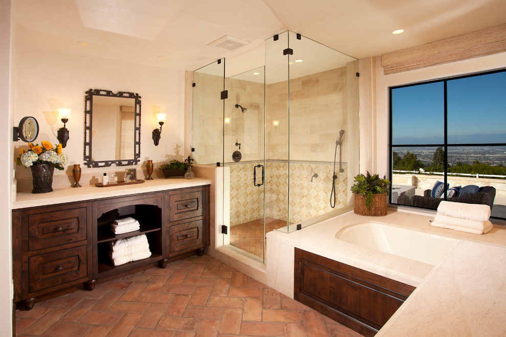 Exemple d'une salle de bain principale méditerranéenne en bois foncé avec une baignoire encastrée, une douche d'angle, un carrelage beige, un mur beige, tomettes au sol, un placard avec porte à panneau surélevé, un sol beige et une fenêtre.