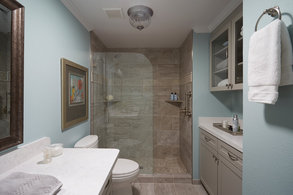 Inspiration pour une salle de bain traditionnelle de taille moyenne avec un placard avec porte à panneau encastré, des portes de placard grises, WC séparés, un carrelage gris, des carreaux de porcelaine, un mur bleu, un sol en carrelage de porcelaine, un lavabo encastré et un plan de toilette en surface solide.
