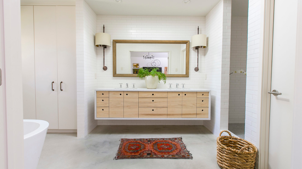 Cette image montre une salle de bain minimaliste en bois clair avec un lavabo encastré, un placard à porte plane, une baignoire indépendante, une douche ouverte, un carrelage blanc, un carrelage métro et aucune cabine.