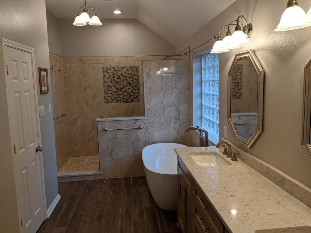 Mid-sized elegant master beige tile and marble tile wood-look tile floor, brown floor and double-sink bathroom photo in Houston with shaker cabinets, medium tone wood cabinets, a one-piece toilet, gray walls, an undermount sink, quartz countertops, beige countertops and a built-in vanity