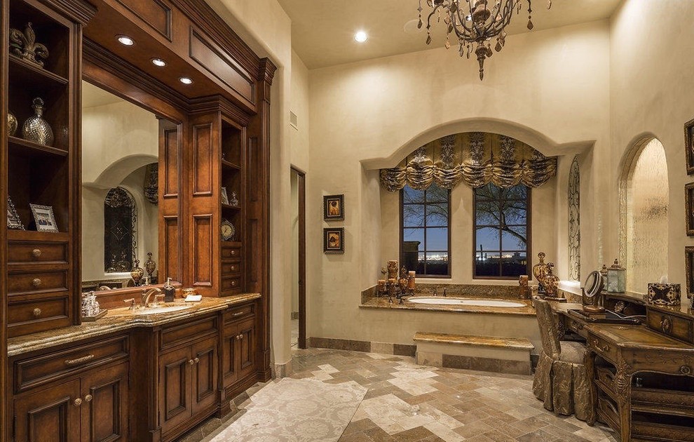 Example of a large tuscan master beige tile and stone slab travertine floor bathroom design in Phoenix with recessed-panel cabinets, dark wood cabinets, a one-piece toilet, beige walls, a drop-in sink and granite countertops