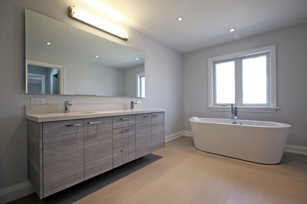 Exempel på ett modernt badrum, med ett undermonterad handfat, ett fristående badkar, beige kakel och grå väggar