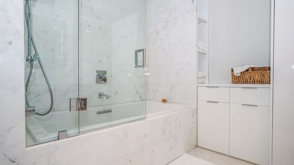 Contemporary ensuite bathroom in Miami with flat-panel cabinets, white cabinets, a built-in bath, a shower/bath combination, white tiles, stone tiles, white walls, marble flooring and engineered stone worktops.
