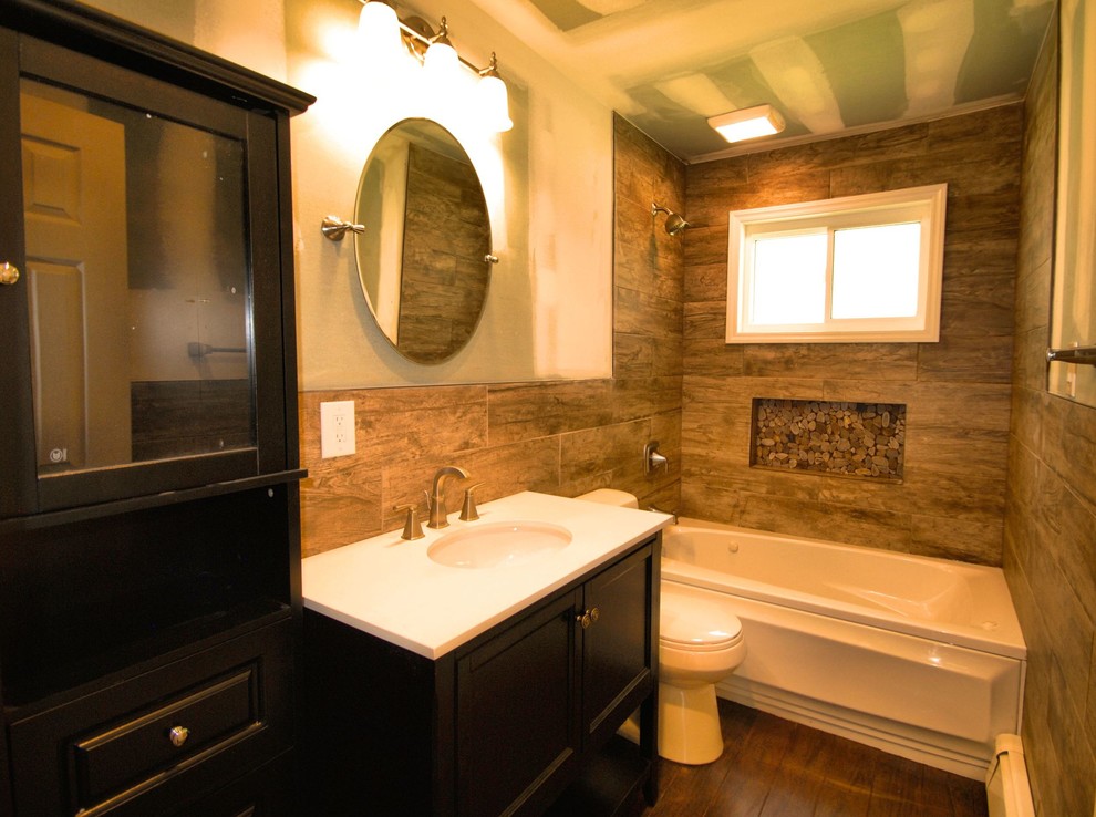 Photo of a medium sized rustic bathroom in New York with open cabinets, black cabinets, an alcove bath, a shower/bath combination, a two-piece toilet, brown tiles, porcelain tiles, porcelain flooring, a submerged sink and engineered stone worktops.