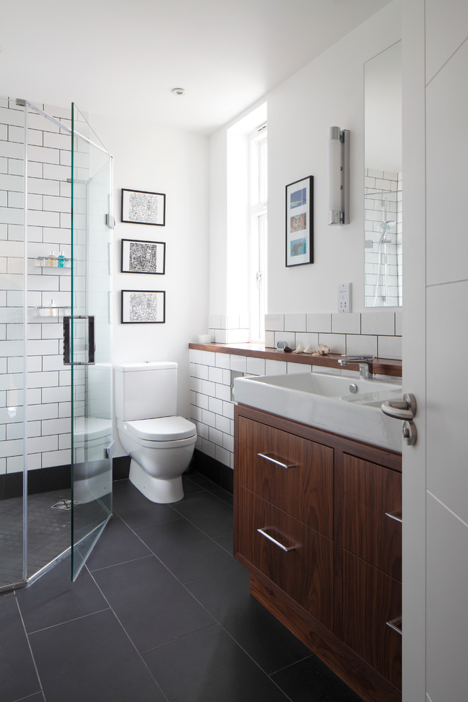 Inspiration for a small contemporary kids' white tile and ceramic tile gray floor, slate floor and double-sink corner shower remodel in London with an integrated sink, flat-panel cabinets, dark wood cabinets, white walls, a one-piece toilet, wood countertops, a hinged shower door, brown countertops and a built-in vanity