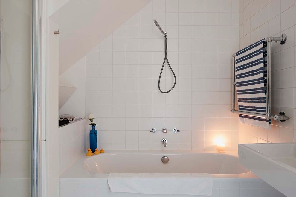 Small contemporary family bathroom in Dublin with a built-in bath, a built-in shower, a wall mounted toilet, white tiles, white walls, terrazzo flooring, a wall-mounted sink, white floors and a hinged door.
