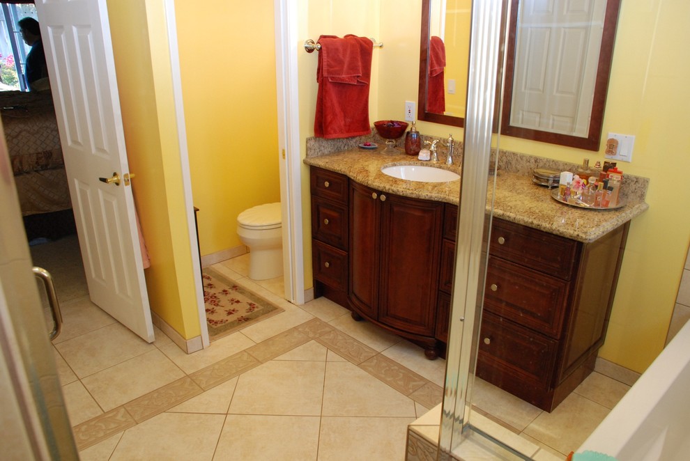 Example of a large trendy master beige tile and ceramic tile ceramic tile bathroom design in Orange County with an undermount sink, furniture-like cabinets, distressed cabinets, granite countertops, a two-piece toilet and yellow walls