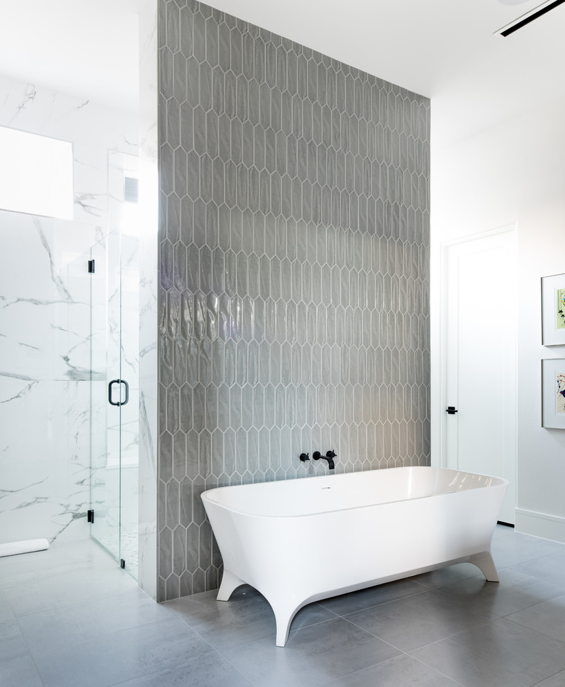 Immagine di una stanza da bagno design con vasca freestanding, doccia a filo pavimento, piastrelle grigie, pareti bianche, pavimento grigio e porta doccia a battente