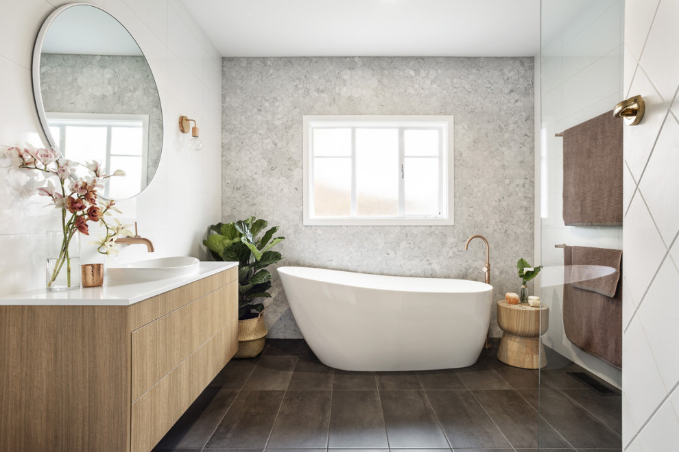 Cette image montre une grande salle de bain principale design en bois brun avec une baignoire indépendante, un carrelage blanc, des carreaux de porcelaine, un sol en carrelage de porcelaine, un sol gris et un plan de toilette blanc.