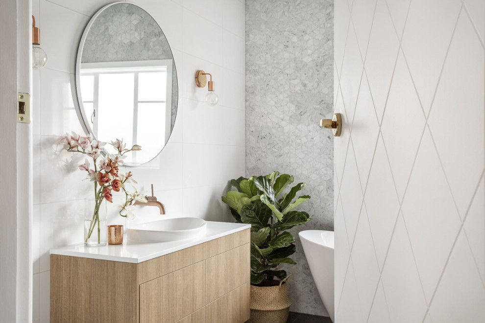 На фото: большая главная ванная комната в современном стиле с фасадами цвета дерева среднего тона, отдельно стоящей ванной, белой плиткой, керамогранитной плиткой, полом из керамогранита, серым полом и белой столешницей