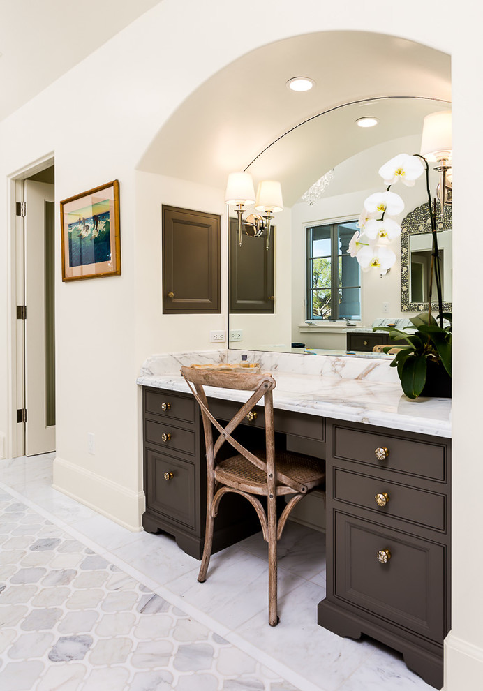 Photo of a classic ensuite bathroom in Los Angeles with recessed-panel cabinets, brown cabinets, a corner shower, a one-piece toilet, white walls, a submerged sink, marble worktops and a hinged door.