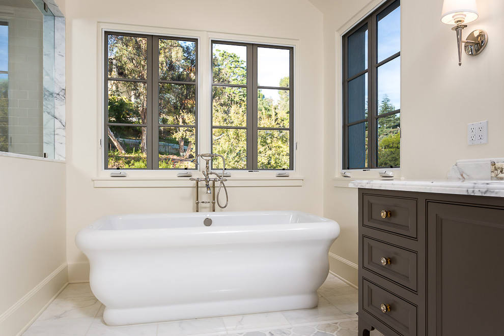 Design ideas for a classic ensuite bathroom in Los Angeles with recessed-panel cabinets, brown cabinets, a freestanding bath, a corner shower, a one-piece toilet, white walls, a submerged sink, marble worktops and a hinged door.
