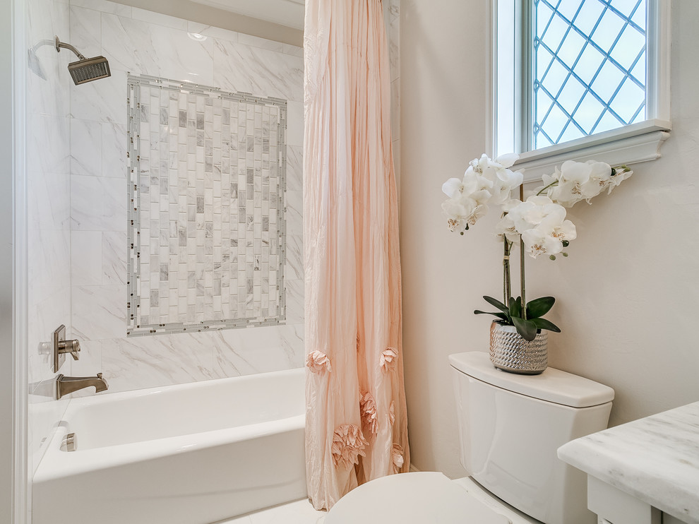 Cette image montre une salle de bain traditionnelle de taille moyenne pour enfant avec un placard en trompe-l'oeil, des portes de placard blanches, une baignoire posée, un combiné douche/baignoire, WC séparés, un carrelage blanc, des carreaux de porcelaine, un mur beige, un sol en carrelage de porcelaine, un lavabo encastré, un plan de toilette en marbre, un sol blanc et une cabine de douche avec un rideau.