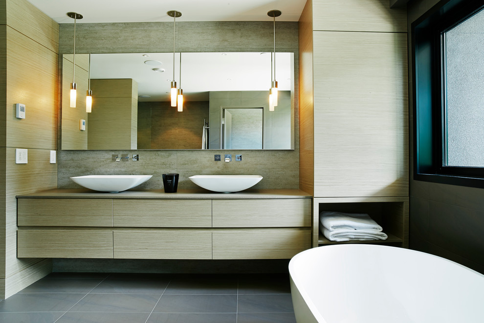 Idéer för ett mellanstort modernt en-suite badrum, med ett fristående handfat, släta luckor, skåp i ljust trä, bänkskiva i kvarts, ett fristående badkar, en öppen dusch, grå kakel, porslinskakel, grå väggar och klinkergolv i porslin