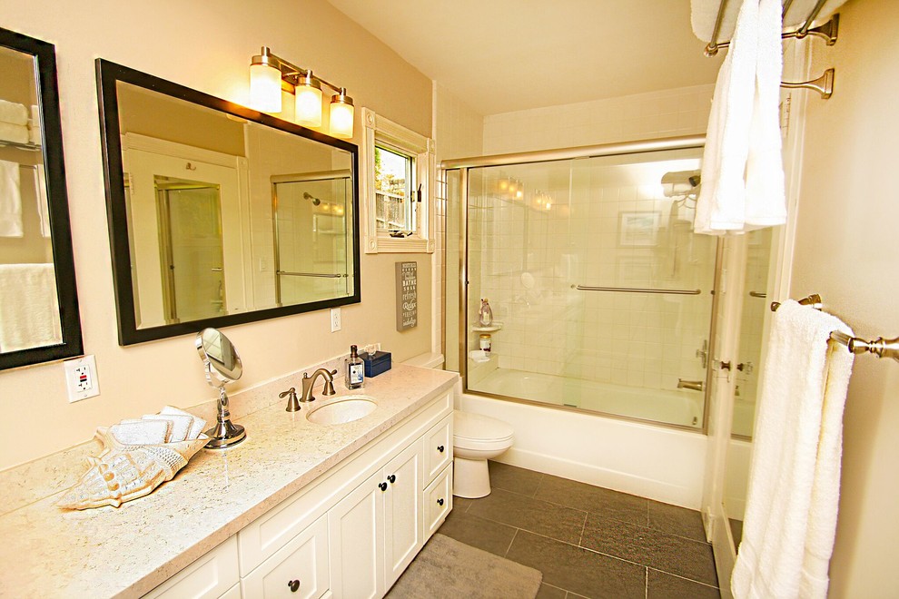 Imagen de cuarto de baño clásico renovado de tamaño medio con armarios estilo shaker, puertas de armario blancas, bañera empotrada, combinación de ducha y bañera, baldosas y/o azulejos blancos, paredes beige y lavabo bajoencimera