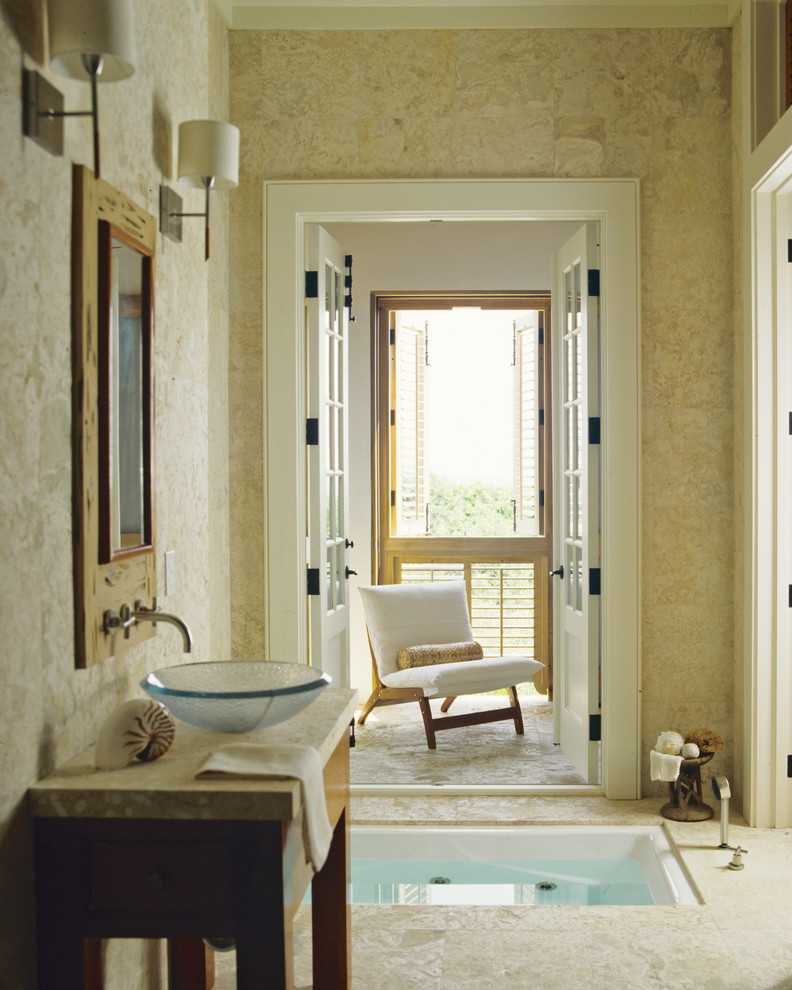 Cette image montre une salle de bain principale ethnique en bois brun de taille moyenne avec un bain bouillonnant, un mur beige, une vasque, un placard sans porte et un sol en carrelage de céramique.