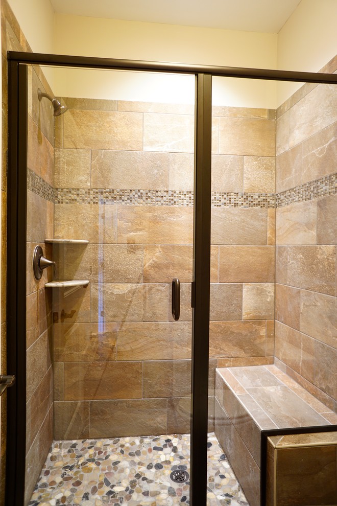 Photo of a contemporary shower room bathroom in Raleigh with raised-panel cabinets, dark wood cabinets, an alcove shower, a two-piece toilet, beige tiles, pebble tiles, beige walls, ceramic flooring, a submerged sink and granite worktops.