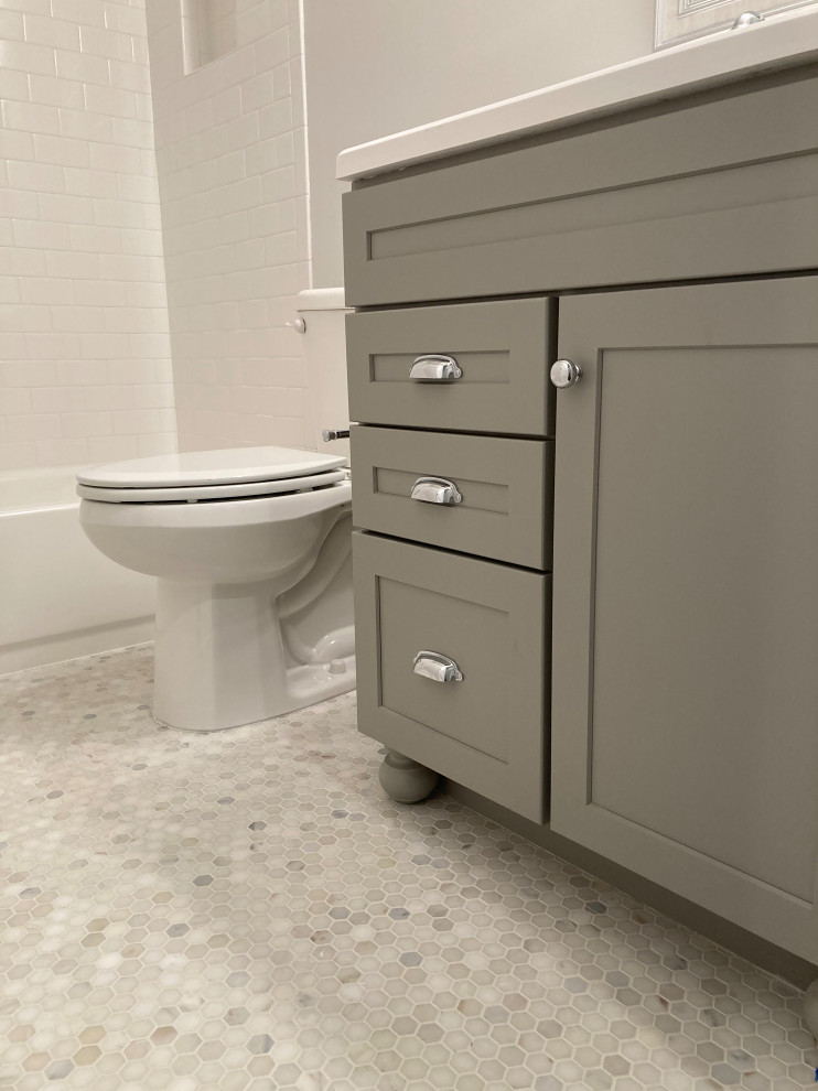 Photo of a medium sized traditional family bathroom in DC Metro with recessed-panel cabinets, grey cabinets, an alcove bath, a shower/bath combination, a two-piece toilet, white tiles, metro tiles, grey walls, mosaic tile flooring, an integrated sink, solid surface worktops, multi-coloured floors, a shower curtain, white worktops, a wall niche, a single sink and a built in vanity unit.