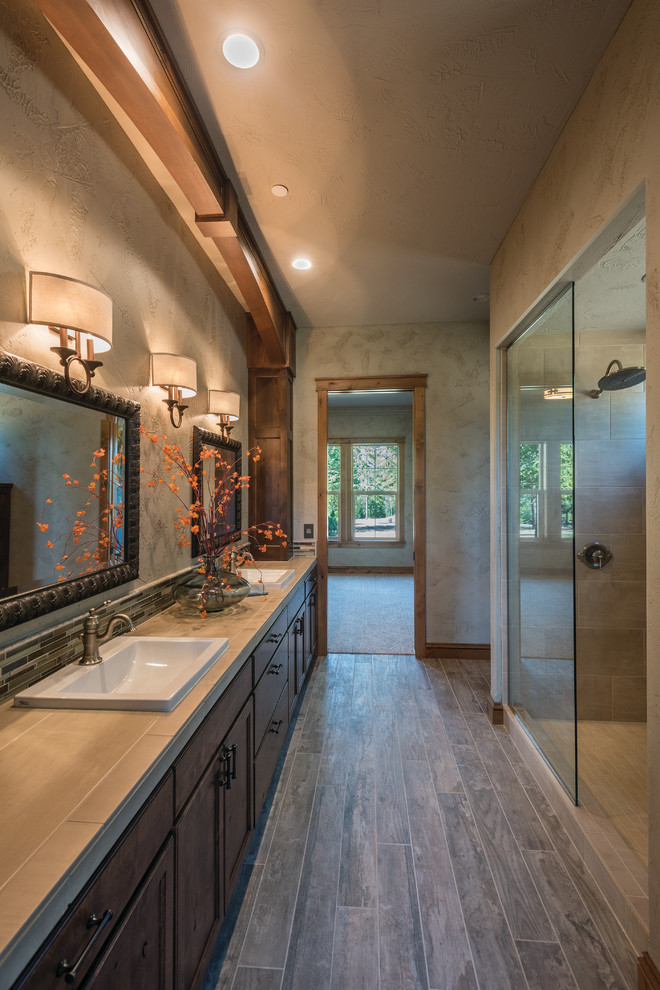 Example of a large trendy master beige tile and stone tile dark wood floor and brown floor bathroom design in Seattle with recessed-panel cabinets, dark wood cabinets, a two-piece toilet, beige walls, a drop-in sink, laminate countertops and beige countertops