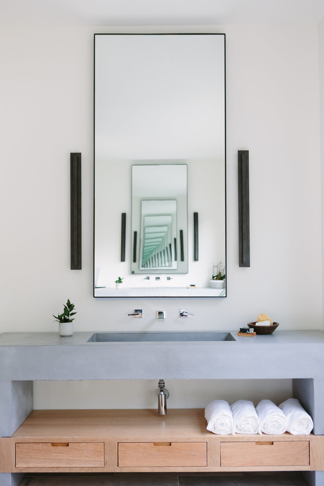 Example of a beach style bathroom design in Nashville with flat-panel cabinets, light wood cabinets, white walls, an integrated sink, gray countertops and concrete countertops