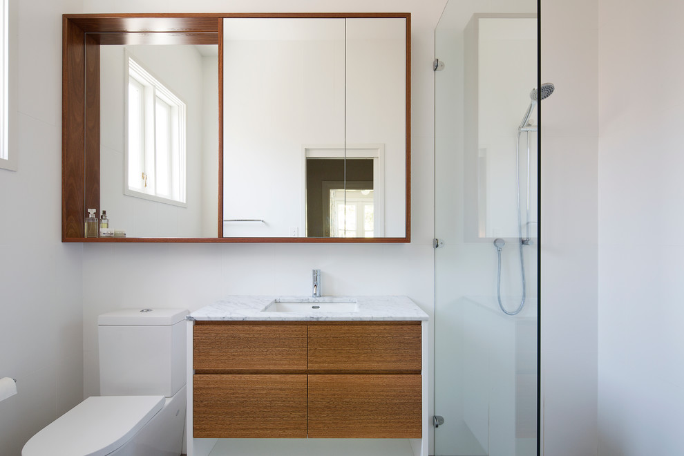 Photo of a contemporary bathroom in Sydney with flat-panel cabinets, medium wood cabinets, a walk-in shower, a two-piece toilet, white tiles, white walls, a submerged sink and an open shower.