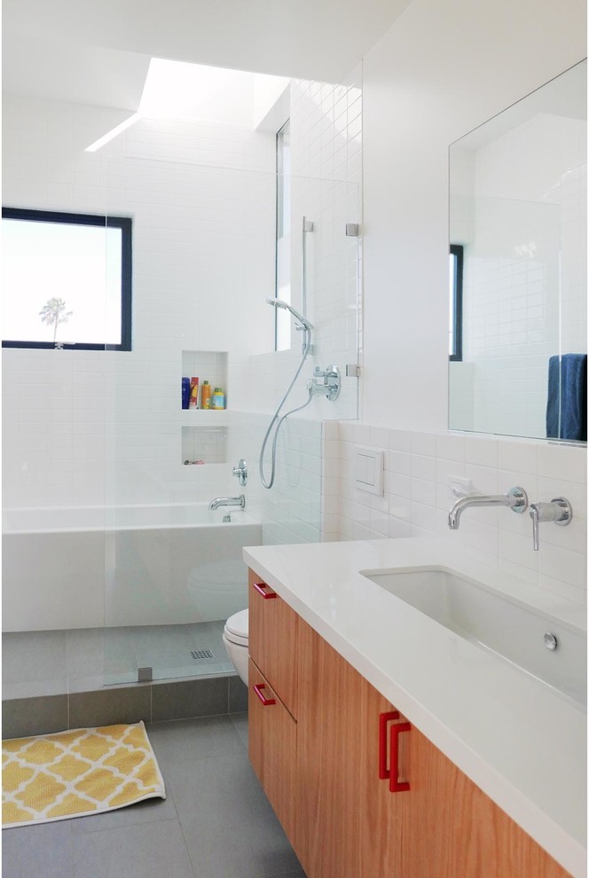 Medium sized contemporary bathroom in Los Angeles with an open shower, flat-panel cabinets, medium wood cabinets, an alcove bath, a two-piece toilet, white tiles, metro tiles, white walls, slate flooring, a trough sink, quartz worktops and grey floors.