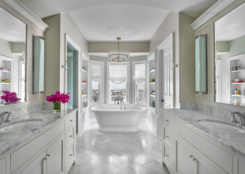 Photo of a classic bathroom in Chicago with shaker cabinets, white cabinets, a freestanding bath, beige walls, a submerged sink and white floors.