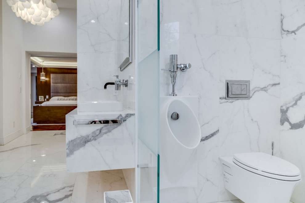 Inredning av ett klassiskt stort vit vitt en-suite badrum, med öppna hyllor, skåp i mörkt trä, ett fristående badkar, en hörndusch, ett urinoar, vit kakel, marmorkakel, marmorgolv, ett väggmonterat handfat, marmorbänkskiva, vitt golv och dusch med gångjärnsdörr