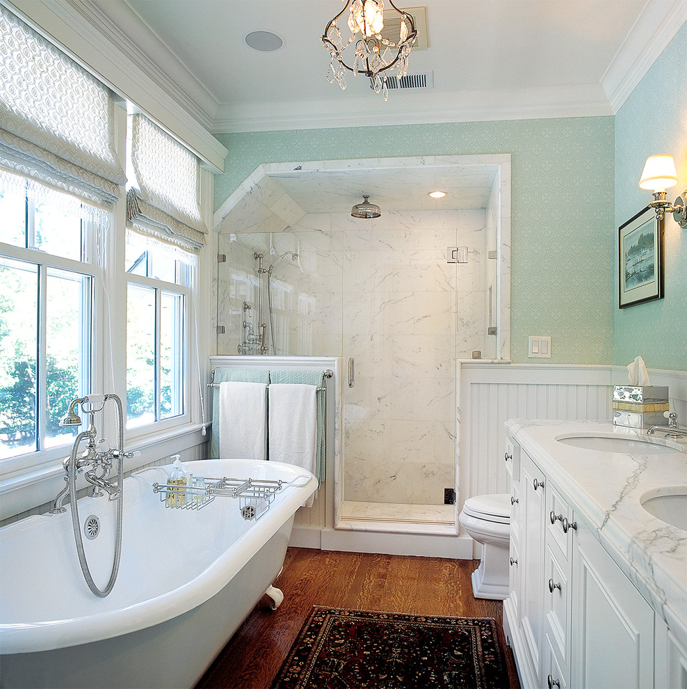 Réalisation d'une salle de bain victorienne avec une baignoire sur pieds, un plan de toilette en marbre et du carrelage en marbre.