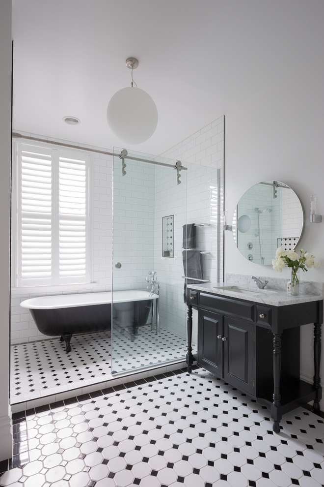 Modelo de cuarto de baño principal y azulejo de dos tonos, tradicional, con puertas de armario negras, bañera con patas, combinación de ducha y bañera, baldosas y/o azulejos de vidrio, paredes blancas, suelo de baldosas de cerámica, lavabo bajoencimera y armarios con paneles con relieve
