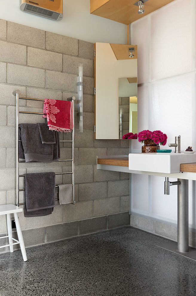 Großes Industrial Badezimmer mit weißer Wandfarbe, Betonboden, Waschtisch aus Holz, brauner Waschtischplatte, Aufsatzwaschbecken und grauem Boden in Hamilton