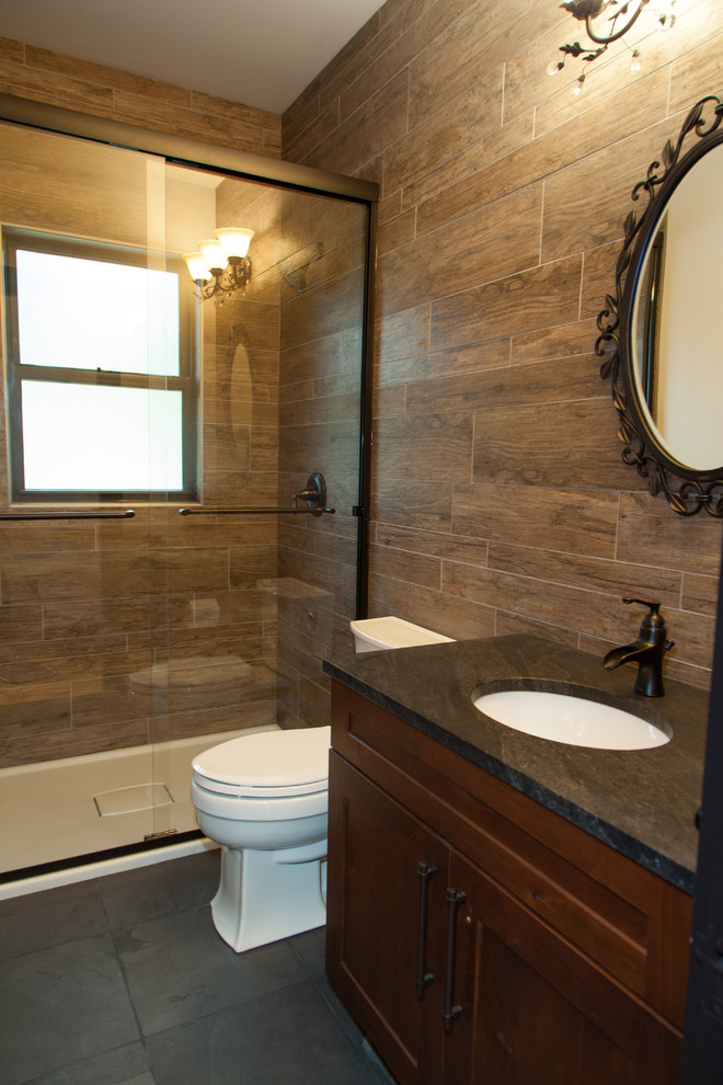 Cette image montre une salle de bain chalet en bois foncé de taille moyenne avec un lavabo encastré, un placard à porte shaker, un plan de toilette en granite, un carrelage marron, des carreaux de porcelaine et un sol en ardoise.