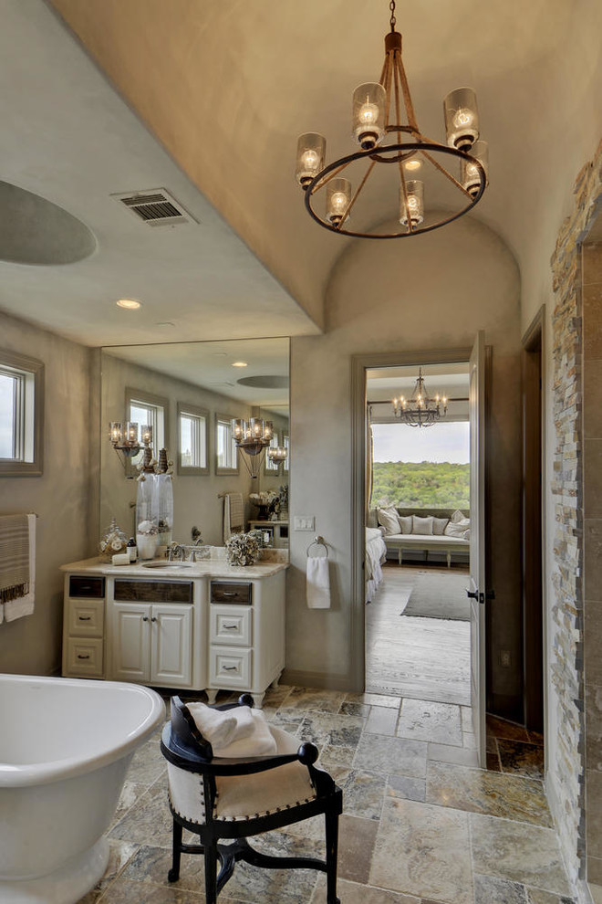 Design ideas for a mediterranean bathroom in Dallas with a submerged sink, raised-panel cabinets, white cabinets, a freestanding bath, an alcove shower, beige tiles, beige walls and beige floors.