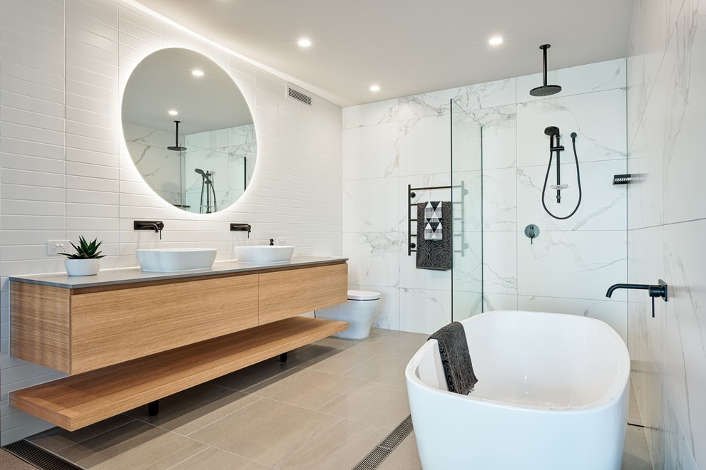 Foto di una stanza da bagno design con ante lisce, ante in legno scuro, vasca freestanding, piastrelle bianche, lavabo a bacinella, pavimento grigio e top grigio
