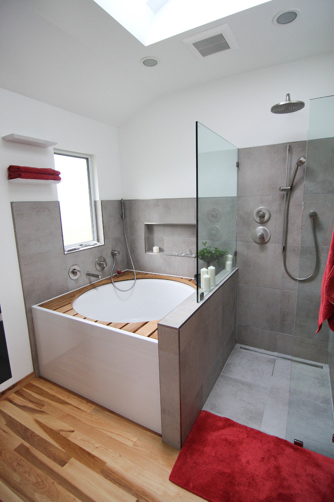 Cette image montre une salle de bain principale design en bois foncé de taille moyenne avec un placard à porte plane, un bain japonais, une douche à l'italienne, WC suspendus, un carrelage gris, des carreaux de céramique, un mur blanc, parquet clair et un lavabo suspendu.
