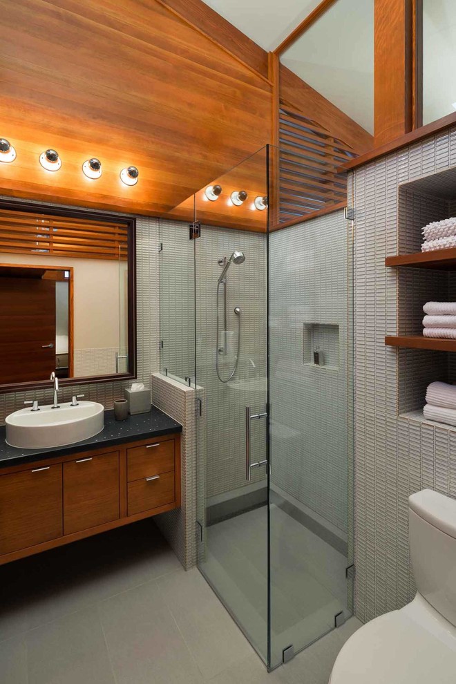 Cette photo montre une petite salle d'eau moderne en bois brun avec une vasque, un placard à porte plane, une douche à l'italienne, WC à poser, un carrelage gris, un carrelage de pierre, un mur blanc et un sol en carrelage de céramique.