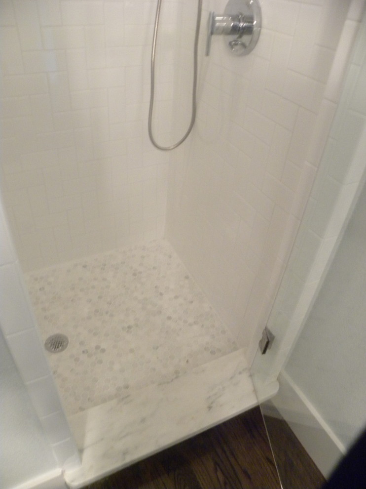 Bild på ett amerikanskt badrum, med skåp i shakerstil, vita skåp, ett platsbyggt badkar, en hörndusch, en toalettstol med separat cisternkåpa, vit kakel, keramikplattor, grå väggar, mellanmörkt trägolv, ett undermonterad handfat och bänkskiva i kvarts