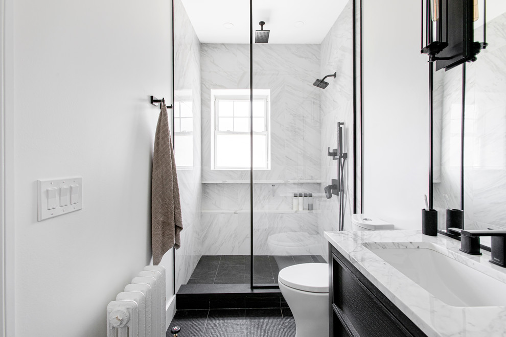 Cette image montre une salle de bain principale minimaliste avec des portes de placard noires, WC séparés, du carrelage en marbre, un mur blanc, un sol en carrelage de porcelaine, un sol noir et aucune cabine.