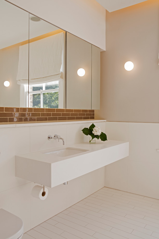 Photo of a contemporary bathroom in London with solid surface worktops, beige walls and a submerged sink.