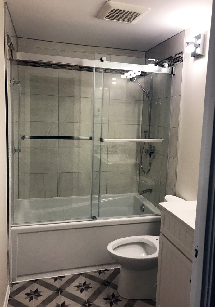 Foto på ett litet vintage vit badrum, med vita skåp, ett hörnbadkar, en dusch/badkar-kombination, en bidé, grå kakel, keramikplattor, vita väggar, klinkergolv i keramik, ett integrerad handfat, bänkskiva i kvarts, grått golv och dusch med skjutdörr