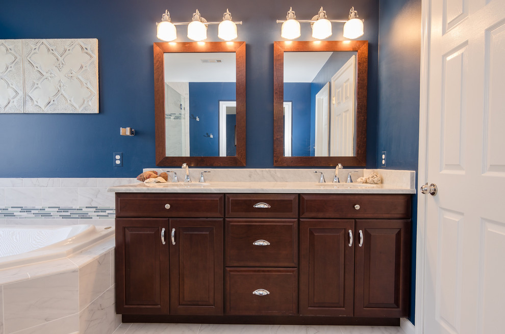 Large traditional ensuite bathroom in DC Metro with a submerged sink, raised-panel cabinets, medium wood cabinets, granite worktops, a built-in bath, a corner shower, a two-piece toilet, white tiles, porcelain tiles, blue walls and porcelain flooring.