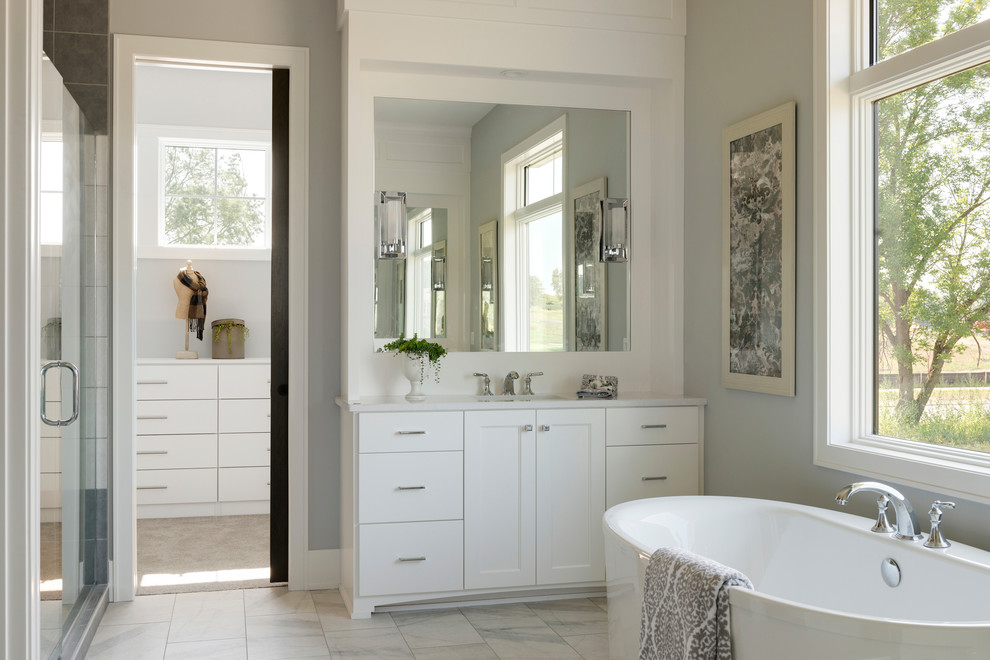 Источник вдохновения для домашнего уюта: главная ванная комната в стиле неоклассика (современная классика) с белыми фасадами, отдельно стоящей ванной, серыми стенами, врезной раковиной, белым полом и белой столешницей