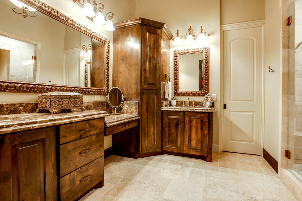 Inspiration for a large timeless brown tile and stone slab travertine floor bathroom remodel in Dallas with an integrated sink, raised-panel cabinets, dark wood cabinets, granite countertops, a one-piece toilet and white walls