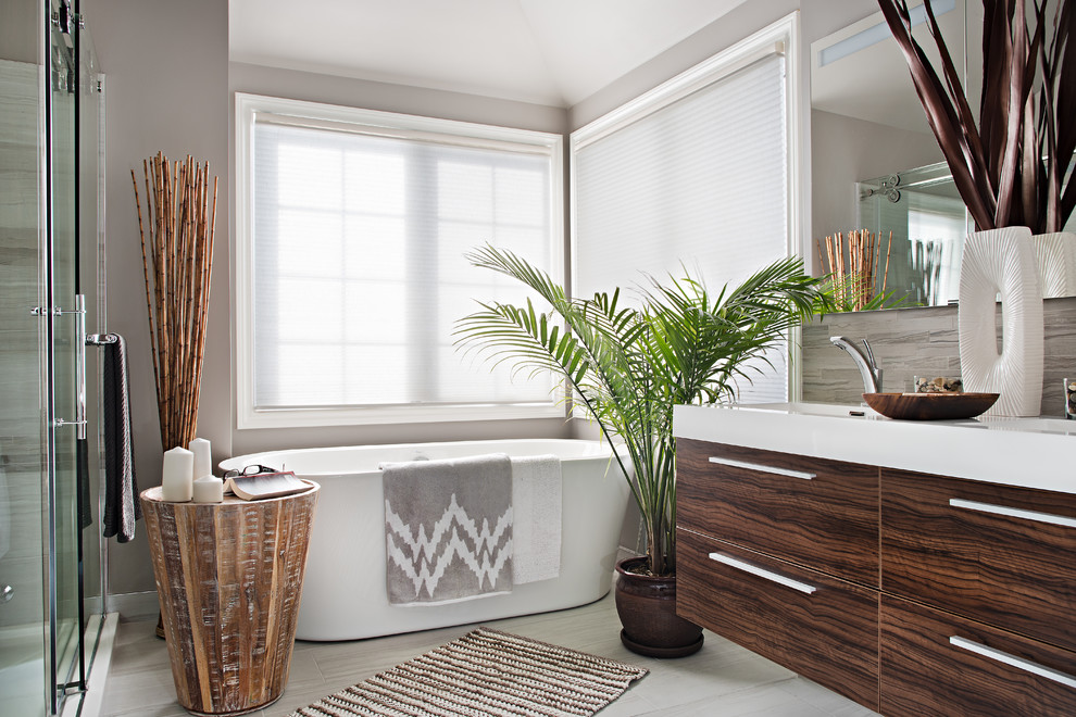 Bild på ett mellanstort tropiskt en-suite badrum, med ett integrerad handfat, släta luckor, skåp i mellenmörkt trä, bänkskiva i akrylsten, ett fristående badkar, en hörndusch, en toalettstol med hel cisternkåpa, beige kakel, keramikplattor, grå väggar och klinkergolv i keramik