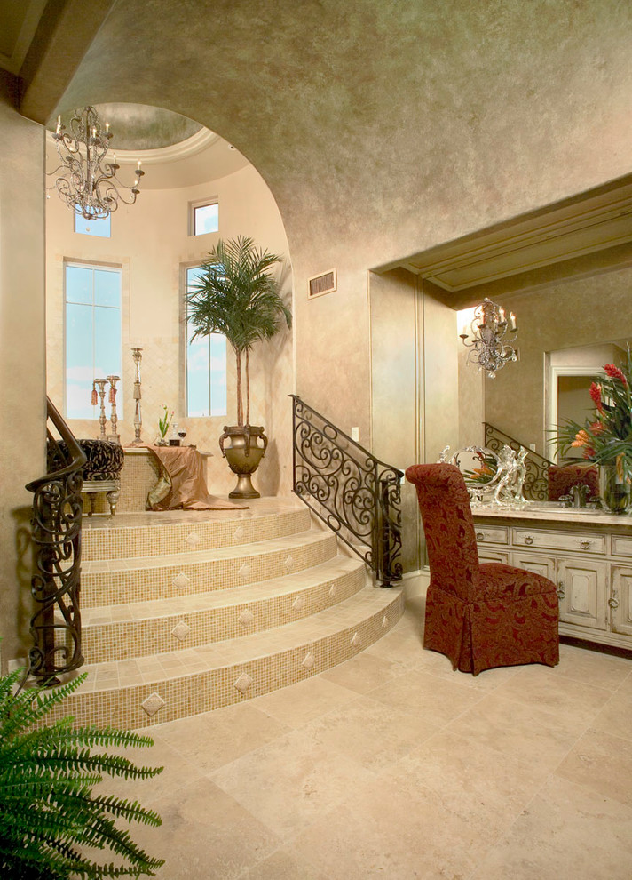 На фото: огромная ванная комната в средиземноморском стиле с фасадами островного типа, светлыми деревянными фасадами, столешницей из гранита, накладной ванной, открытым душем, бежевой плиткой, каменной плиткой, бежевыми стенами и полом из травертина с