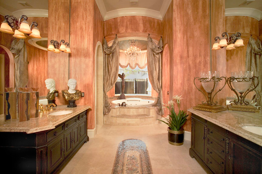 Ispirazione per un'ampia stanza da bagno padronale mediterranea con consolle stile comò, ante in legno bruno, top in marmo, vasca idromassaggio, piastrelle beige e piastrelle in pietra